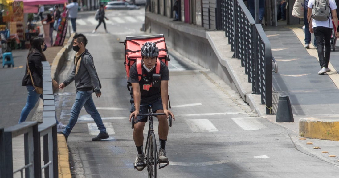 Joven repartidor de comida por aplicación pedalea en las avenidas del Centro.