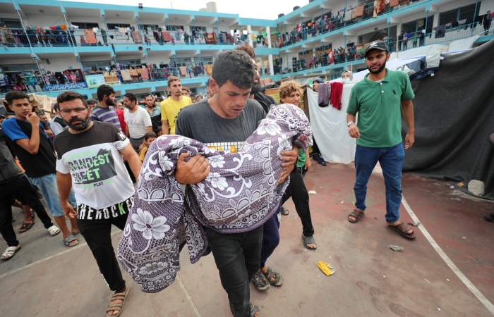 Un palestino lleva en brazos a un niño muerto en un bombardeo israelí sobre la Franja de Gaza, durante su funeral en una escuela gestionada por la ONU, en Deir al Balah, en la Franja de Gaza, el 27 de octubre de 2023.