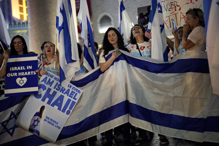 Gente con banderas y pancartas durante una marcha en apoyo de Israel, el domingo 8 de octubre de 2023 en Las Vegas. Los carteles dicen "Israel en nuestros corazones" y "Ahora más que nunca, ¡el pueblo de Israel vive!".