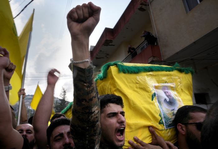 Un combatiente de Hezbollah carga el ataúd de uno de sus compañeros que murió por artillería israelí, mientras grita consignas durante una procesión fúnebre, el martes 10 de octubre de 2023, en el poblado de Khirbet Selm, en el sur de Líbano.