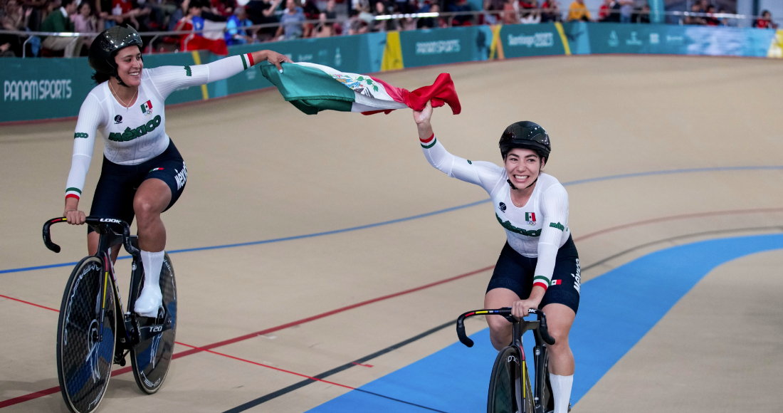 La mexicana Daniela Gaxiola (derecha) y su compañera Jessica Salazar recorren la pista tras ganar la medalla de oro en la carrera de velocidad por equipos de los Juegos Panamericanos en Santiago, Chile, el martes 24 de octubre de 2023.