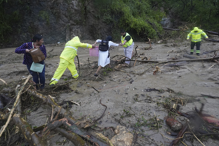 La gente recibe ayuda para cruzar una carretera bloqueada por un deslizamiento de tierra provocado por el huracán "Otis" cerca de Acapulco, México, el miércoles 25 de octubre de 2023.