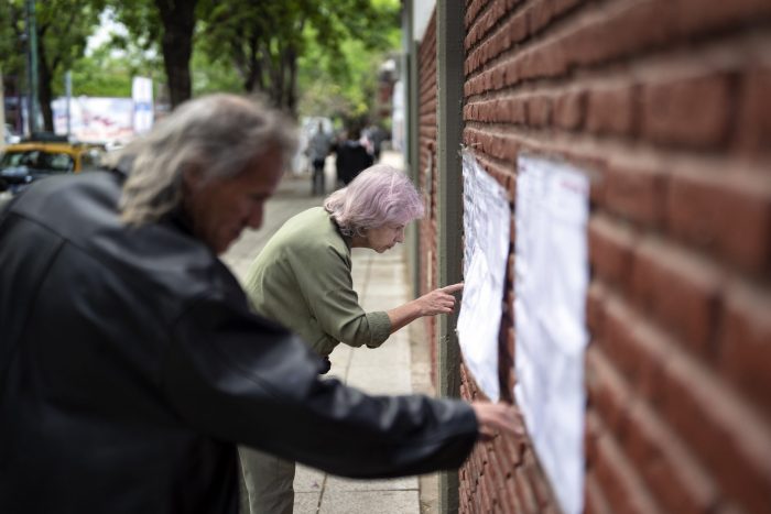 Las personas buscan sus nombres en las listas electorales antes de emitir su voto durante las elecciones generales en Buenos Aires, Argentina, el domingo 22 de octubre de 2023.