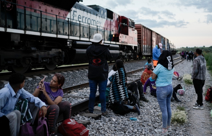 Migrantes observan un tren en marcha junto a las vías en las que esperan para subir a bordo de un vagón con el fin de dirigirse al norte de México, el 19 de septiembre de 2023, en Huehuetoca, México. 