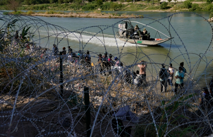 Migrantes que cruzaron a Estados Unidos desde México se encuentran con alambre de púas en la orilla del río Grande, el 21 de septiembre de 2023, en Eagle Pass, Texas. 