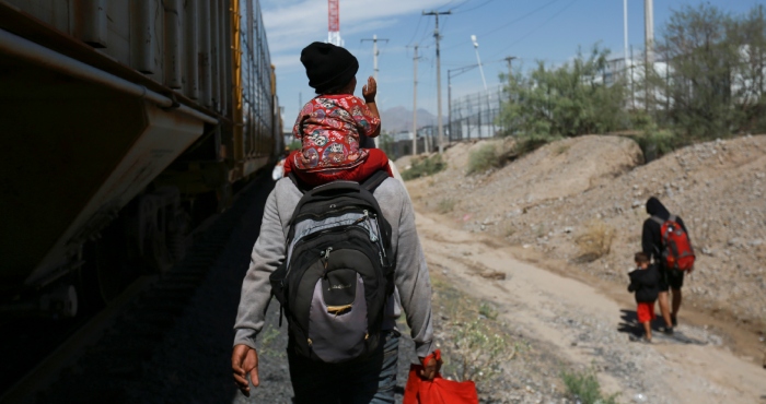 Migrantes caminan junto a un vagón de tren en Ciudad Juárez, México, el jueves 28 de septiembre de 2023.