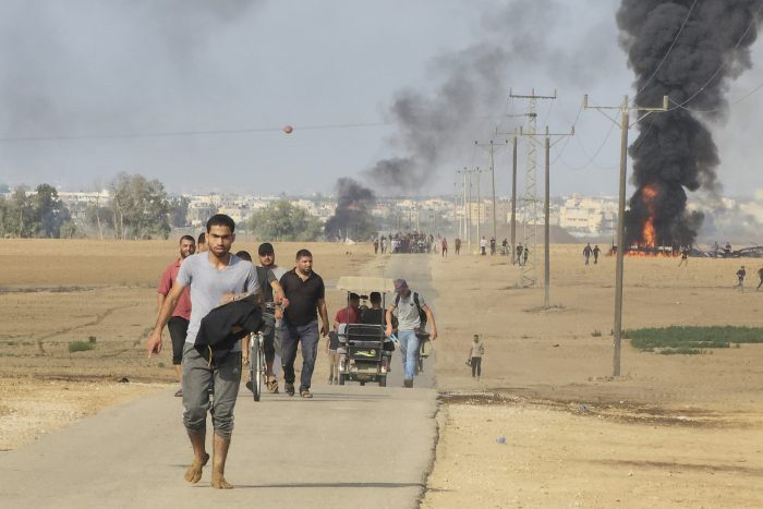 Palestinos se alejan del kibbutz de Kfar Azza, Israel, cerca de la valla fronteriza de la Franja de Gaza, el 7 de octubre de 2023. 