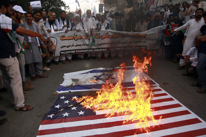 Partidarios de la Fundación Palestina Pakistán queman réplicas de banderas de Israel y Estados Unidos mientras corean lemas contra los ataques aéreos israelíes en Gaza, en una manifestación para solidarizarse con el pueblo palestino, en Karachi Pakistán, el domingo 8 de octubre de 2023.