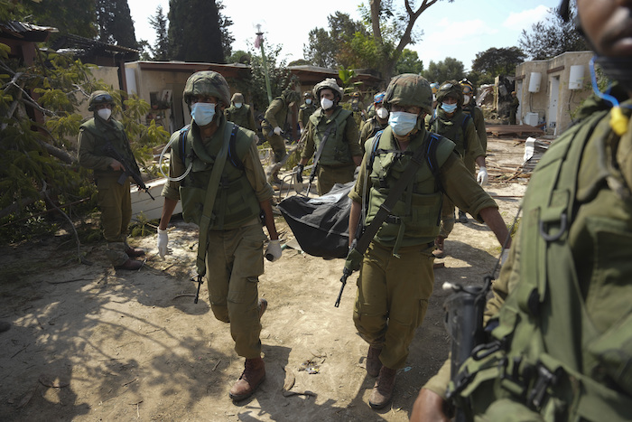 Soldados israelíes cargan el cuerpo de una persona que murió en un ataque de Hamás, el martes 10 de octubre de 2023, en el kibbutz Kfar Aza. Combatientes de Hamás incursionaron el sábado en el kibbutz, donde mataron y secuestraron a varios israelíes.