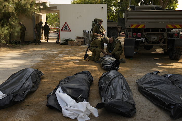 Soldados israelíes junto a los cuerpos de israelíes asesinados por combatientes de Hamás, el martes 10 de octubre de 2023, en el kibutz Kfar Aza. Combatientes de Hamás incursionaron el sábado en Kfar Aza, en donde muchos israelíes fueron asesinados o secuestrados.