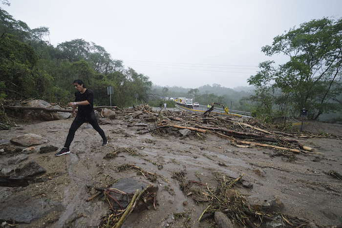 Un hombre cruza una carretera bloqueada por un deslizamiento de tierra provocado por el huracán "Otis" cerca de Acapulco, México, el miércoles 25 de octubre de 2023.