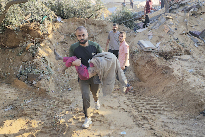 Un palestino lleva a una niña asesinada en ataques aéreos israelíes en Deir el-Balah, en la Franja de Gaza, el domingo 15 de octubre de 2023.