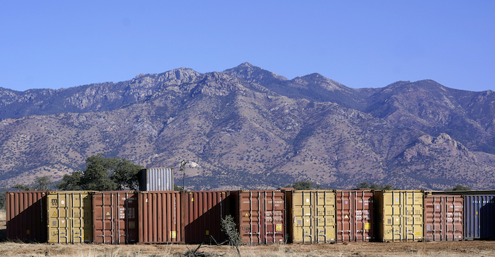 Una larga fila de contenedores espera para ser instalada a lo largo de la frontera donde cientos de contenedores crean un muro entre Estados Unidos y México en el Valle de San Rafael, Arizona, el jueves 8 de diciembre de 2022.