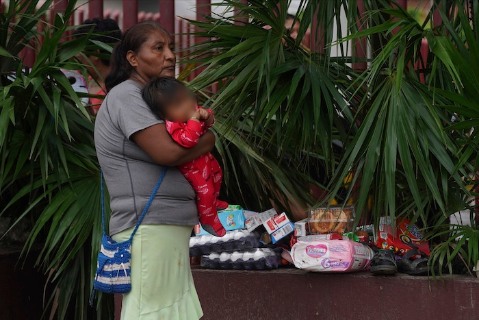 Una mujer sostiene a un bebé en brazos junto a varios objetos saqueados luego del paso del huracán "Otis" por Acapulco, México, el 25 de octubre de 2023.