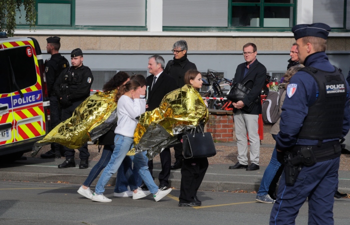 Policías escoltan a niños ante la escuela Gambetta, durante una amenaza de bomba el lunes 16 de octubre de 2023, en Arras, al norte de Francia. El Presidente de Francia, Emmanuel Macron, celebraba el lunes una reunión especial de seguridad en un clima de alerta contra ataques. La escuela secundaria francesa donde un maestro murió apuñalado la semana pasada fue evacuada por una amenaza de bomba.