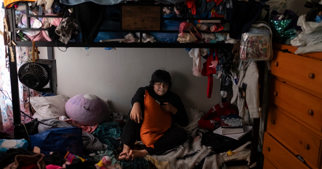 Deneffy Sánchez, de 15 años, descansa en una cama que comparte con su madre y hermanita a unos metros de distancia de la cama de su compañera de piso, el sábado 9 de septiembre de 2023, en Los Ángeles. En esta ciudad, la inseguridad de la vivienda es uno de los motivos más importantes por los que los niños han faltado a la escuela desde la pandemia de COVID-19, lo cual les ha dificultado ponerse al día.