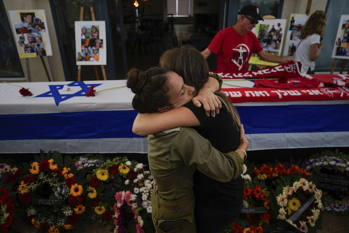 Dos personas se abrazan durante el funeral por Meni y Ayelet Godard, en el kibutz de Palmachim, Israel, el 29 de octubre de 2023.