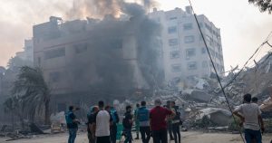 En esta imagen de archivo, reporteros observan mientras palestinos inspeccionan un edificio alcanzado por un bombardeo israelí en la Ciudad de Gaza, 8 de octubre de 2023. El limitado número de periodistas que están en Gaza tratan de informar sobre la guerra con Israel mientras sufren los mismos problemas que la asediada población palestina de la Franja.