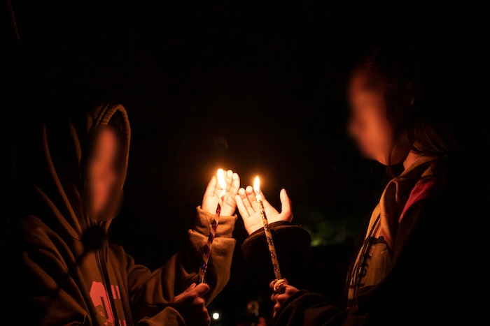 Jóvenes sostienen velas sobre una tumba en un cementerio en Atzompa, México, el martes 31 de octubre de 2023 por la noche.