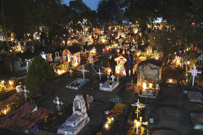 La gente se reúne en la sección de tumbas de niños dentro del cementerio de San Gregorio Atlapulco durante las festividades del Día de Muertos en las afueras de la Ciudad de México, la madrugada del miércoles 1 de noviembre de 2023.