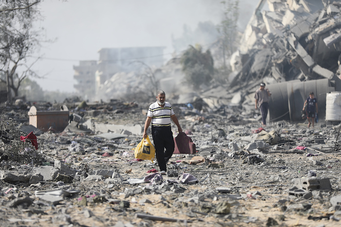 Palestinos caminan entre edificios destruidos por bombardeos israelíes sobre al-Zahra, a las afueras de la Ciudad de Gaza, el 20 de octubre de 2023.