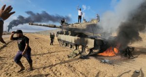 Palestinos celebran junto a un tanque israelí destruido en la cerca fronteriza de la Franja de Gaza, al este de Jan Yunis, en el sur del enclave, el 7 de octubre de 2023.