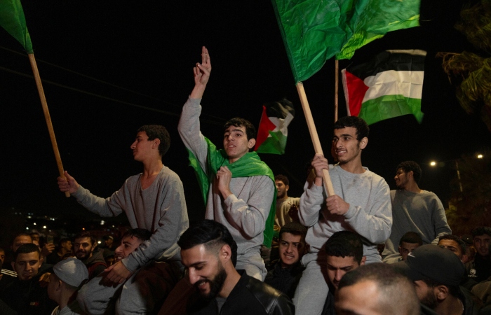 Exprisioneros palestinos liberados por las autoridades israelíes ondean banderas palestinas y de Hamás, mientras son cargados en hombros a su llegada a la localidad de Beitunia, el viernes 24 de noviembre de 2023, en Cisjordania.