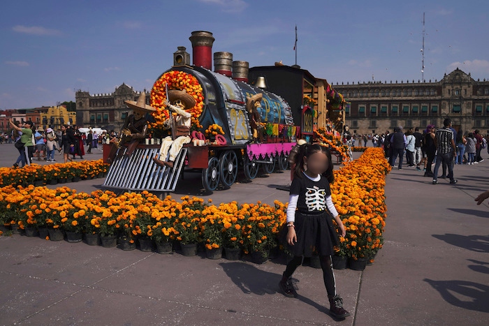 Personas posan para las fotos cerca de una exhibición por el Día de Muertos en el Zócalo, la principal plaza de Ciudad de México, el martes 31 de octubre de 2023.