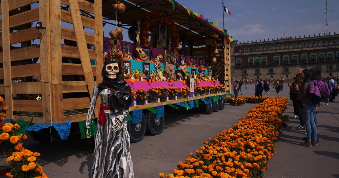 Personas posan para las fotos cerca de una figura de una catrina al lado de un vagón por la celebración del Día de Muertos en el Zócalo, la principal plaza de Ciudad de México, el martes 31 de octubre de 2023.