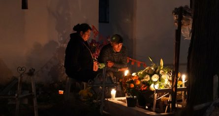 Personas sentadas junto a una tumba en el cementerio de San Gregorio Atlapulco durante las festividades del Día de Muertos en las afueras de la Ciudad de México, el miércoles 1 de noviembre de 2023.