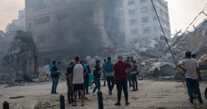 En esta imagen de archivo, reporteros observan mientras palestinos inspeccionan un edificio alcanzado por un bombardeo israelí en la Ciudad de Gaza, 8 de octubre de 2023.