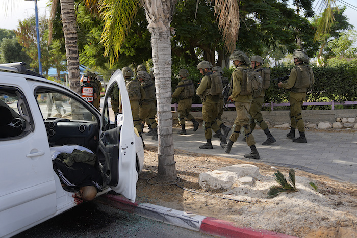 Soldados israelíes pasan junto a un civil asesinado por insurgentes de Hamás en Sderot, Israel, el 7 de octubre de 2023.