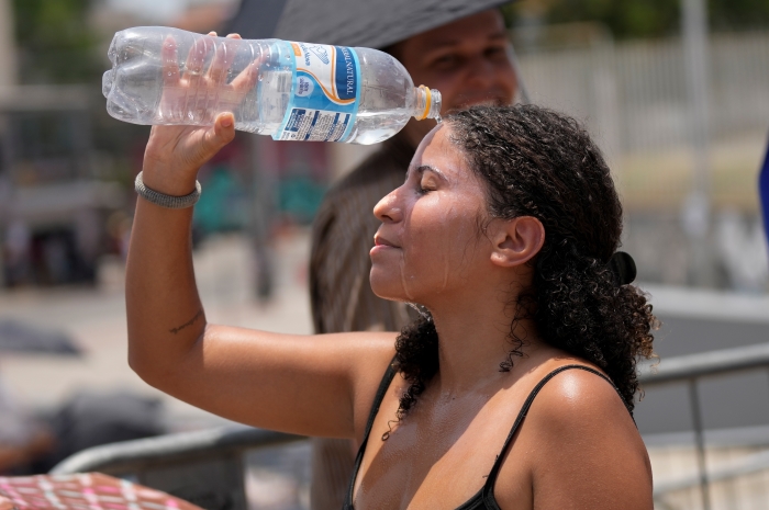 Una seguidora de Taylor Swift se vierte agua para refrescarse en medio de una ola de calor antes del concierto de la cantante, afuera del Estadio Olímpico Nilton Santos de Río de Janeiro, Brasil, el sábado 18 de noviembre de 2023.