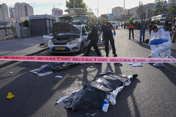 Un agente de policía israelí apunta su arma al cuerpo de un hombre implicado en un ataque en Jerusalén, el jueves 30 de noviembre de 2023. Dos hombres dispararon contra la gente en una estación de autobús en la entrada de Jerusalén, donde dejaron varios muertos y heridos, según la policía.