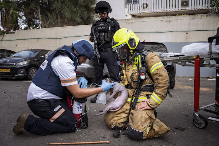 Un bombero y un paramédico administran oxígeno a un gato herido rescatado de un edificio alcanzado por un proyectil disparado desde Gaza, en Tel Aviv, Israel, el 27 de octubre de 2023.