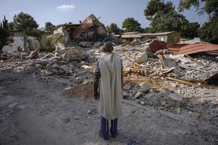 Un hombre israelí, con un chal de rezo, ora junto a viviendas destruidas por insurgentes de Hamás en el kibutz de Be'eri, Israel, el 22 de octubre de 2023. El kibutz fue asaltado por insurgentes de Hamás desde la cercana Gaza el 7 de octubre, cuando mataron y capturaron a muchos israelíes.