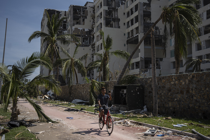 Un hombre pasa en bicicleta por una zona dañada por el huracán "Otis", el domingo 29 de octubre de 2023, en Acapulco, México.