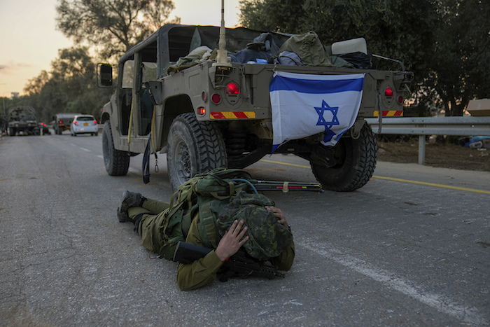 Un soldado israelí cree escuchar una sirena antiaérea y se tira al piso en el kibutz de Be'eri, Israel, el 11 de octubre de 2023.