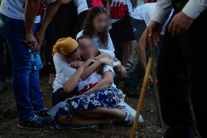 Varias personas lloran junto a las tumbas de las ciudadanas británicas-israelíes Lianne Sharabi y sus dos hijas, Noiya, de 16 años, y Yahel, de 13, durante su funeral en Kfar Harif, Israel, el 25 de octubre de 2023. Las tres fueron asesinadas por insurgentes de Hamás el 7 de octubre en el kibutz de Be'eri, cerca de la frontera con la Franja de Gaza.