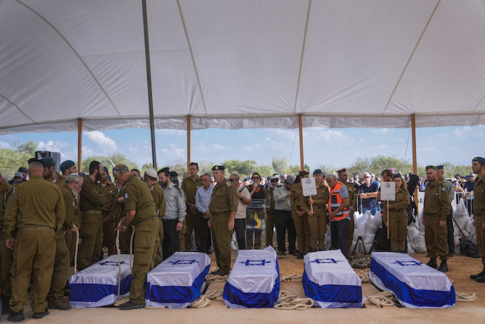 Varias personas se congregan en torno a los ataúdes de cinco miembros de la familia Kotz durante su funeral en Gan Yavne, Israel, el 17 de octubre de 2023. La familia fue asesinada por insurgentes de Hamás el 7 de octubre en su casa en el kibutz de Kfar Azza, cerca de la frontera con la Franja de Gaza.