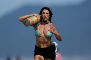 Una deportista compite en una carrera de relevos, cargando troncos, en la playa de Peruibe, como parte de los Juegos Indígenas, cerca de la comunidad Tapirema, en Peruibe, Brasil, el 23 de abril de 2023. 