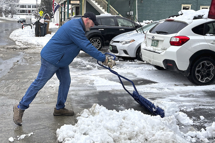 Bobby Searles retira la nieve de un espacio de estacionamiento afuera de la tienda Cabot Village, el lunes 4 de diciembre de 2023, en Cabot, Vermont.