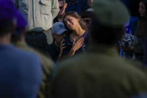 Dos dolientes se reúnen con tristeza alrededor de la tumba del soldado israelí Capitán Harel Ittah durante su funeral en Netanya, Israel, el domingo 31 de diciembre de 2023.