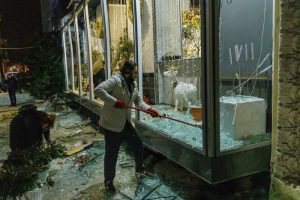 Un hombre limpia vidrios rotos en el escaparate de una tienda después de un ataque con misiles rusos en Kharkiv, Ucarnia, el domingo 31 de diciembre de 2023.