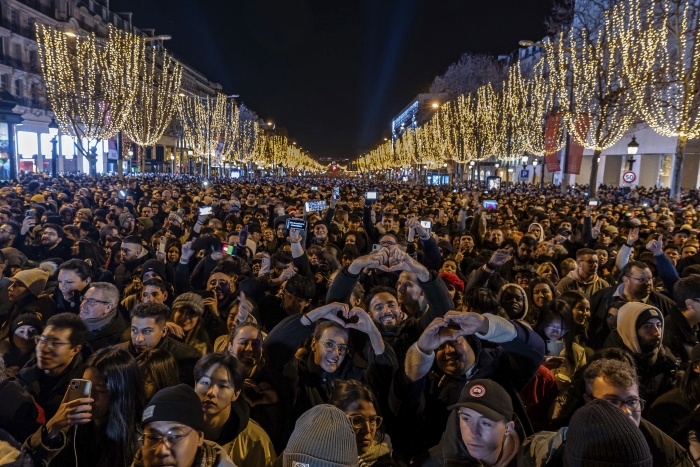 La gente mira un espectáculo de luces proyectado en el Arco de Triunfo mientras celebran el Año Nuevo en los Campos Elíseos de París, en Francia, el domingo 31 de diciembre de 2023.