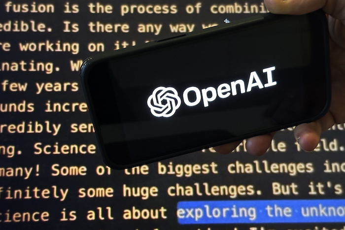 El logo de OpenAI aparece en un celular delante de una pantalla que muestra parte del sitio web de la compañía, en fotografía tomada el 21 de noviembre de 2023 en Nueva York.