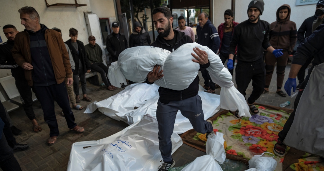 Un hombre palestino carga con el cadáver de un familiar muerto en un bombardeo israelí sobre la Franja de Gaza, en el exterior de una morgue en Rafah, en el sur del enclave, el 29 de diciembre de 2023. Foto: Fatima Shbair, AP