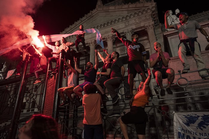 Manifestantes corean consignas antigubernamentales en las rejas que protegen el Congreso Nacional durante una protesta contra las medidas económicas del Gobierno, el jueves 21 de diciembre de 2023, en Buenos Aires, Argentina.