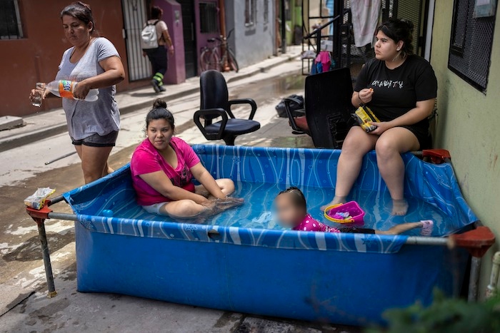 Miembros de la familia Sánchez se refrescan en una piscina de plástico fuera de su casa en el barrio Padre Carlos Múgica de Buenos Aires, Argentina, el miércoles 13 de diciembre de 2023.