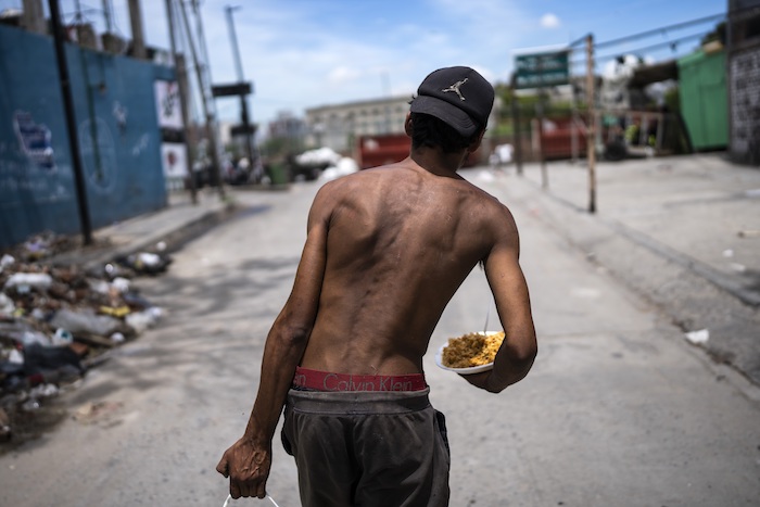 Nicolás Gonzáles camina con un plato de comida a la salida de la Casa Comunitaria del Fondo en el barrio Padre Carlos Múgica de Buenos Aires, Argentina, el miércoles 13 de de diciembre de 2023.